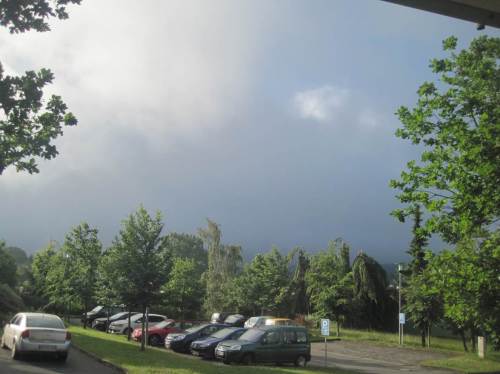 Die Autos sind schon weitgehend beladen, über den Bergen kämpft noch der Hochnebel nach Gewitterregen mit der Sonne.