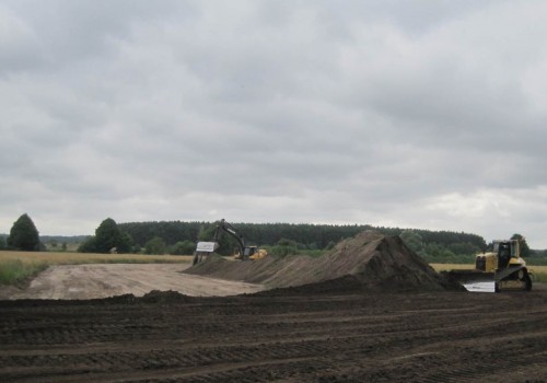Plötzlich ist es wolkig und windiger geworden. - Am Ostufer sind Bagger und Raupe dabei, den Mutterboden wieder auf die Trasse aufzubringen.