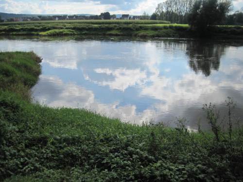 Der Himmel spiegelt sich auf klarem Weserwasser im Buhnenfeld.