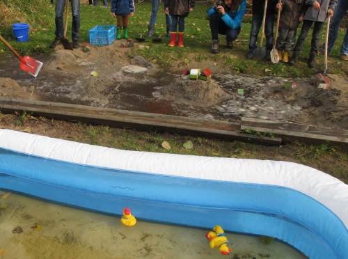 Den Besuchern wird mehr geboten. Aus einem aufgestauten Teich kann gezielt Wasser in einen modellartigen Talraum geleitet werden. - Oje, da stehen ja Häuser.